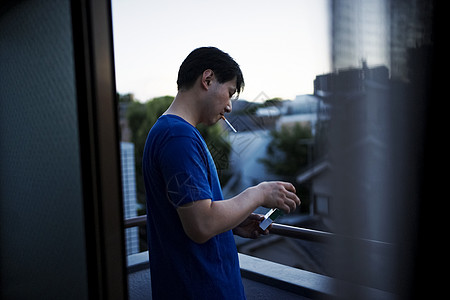 站在阳台抽烟的成年男子图片素材