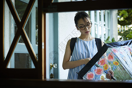 收伞回到室内的年轻女孩图片