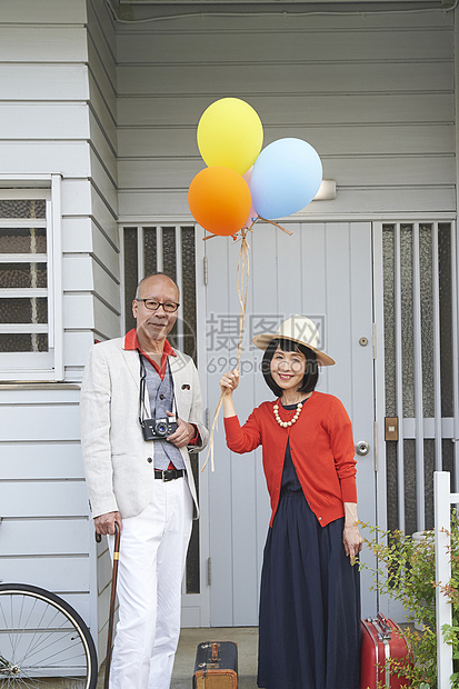 房屋前时髦的中老年夫妇手拿气球图片