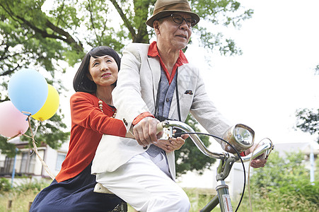 双人自行车公园里骑自行车的中老年夫妇背景