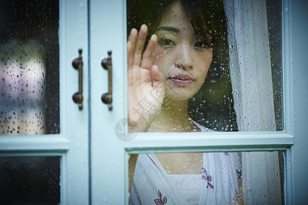 穿过窗口窗格打碎雨天女人在家里度过图片