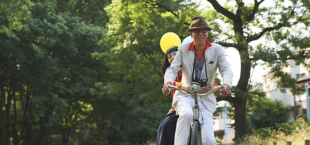 绿地笑脸微笑骑自行车的资深夫妇图片