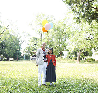 老年夫妇拿气球逛公园画象图片
