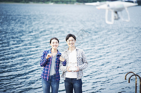 在湖泊旁玩无人机的情侣图片