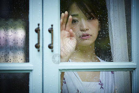 下雨天靠在窗边发呆的孤独女性图片素材