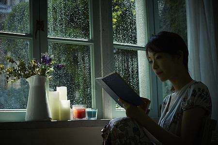 下雨天靠在窗边发呆的孤独女性图片