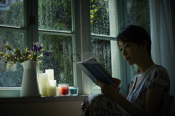 下雨天靠在窗边发呆的孤独女性图片