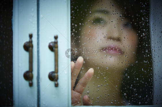 下雨天靠在窗边发呆的孤独女性图片