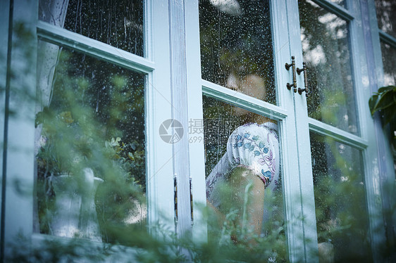 下雨天靠在窗边发呆的女性图片