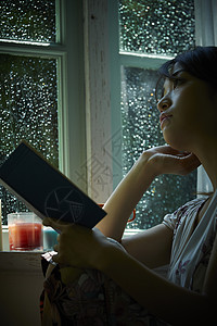 下雨天在窗边读书的孤独女性高清图片