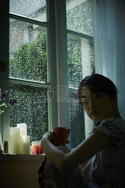 下雨天靠在窗边发呆的女性图片