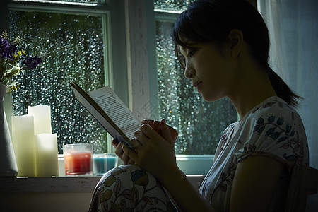 下雨天在窗边读书的孤独女性图片