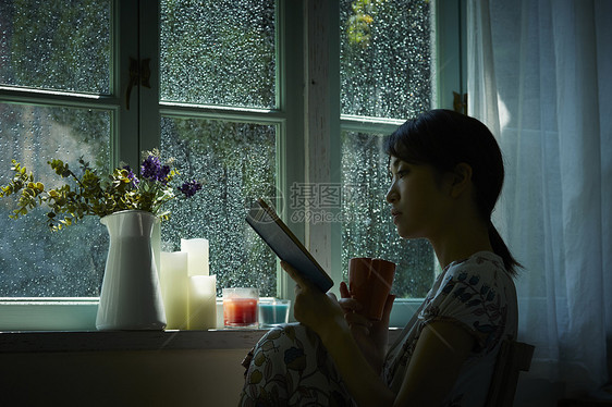 下雨天在窗边读书的孤独女性图片