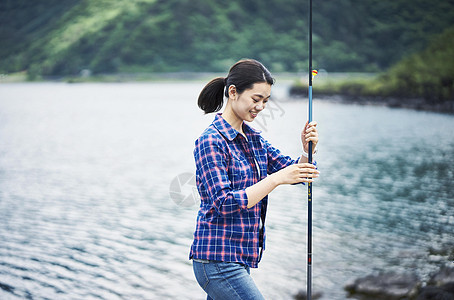 拿着鱼竿开心的年轻女性图片