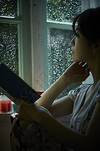 雨天坐在窗边向外看的女性图片