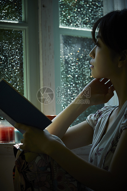 雨天坐在窗边向外看的女性图片