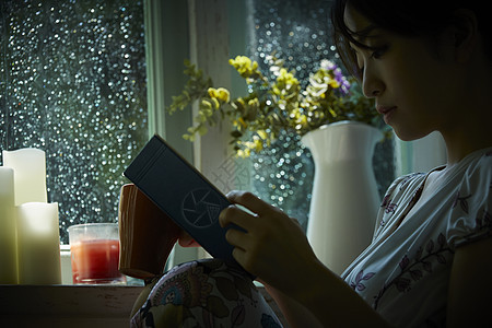 雨天休息在家看书的年轻女性图片