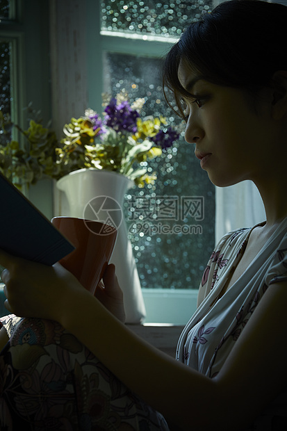 雨天在家看书喝茶的年轻女性图片