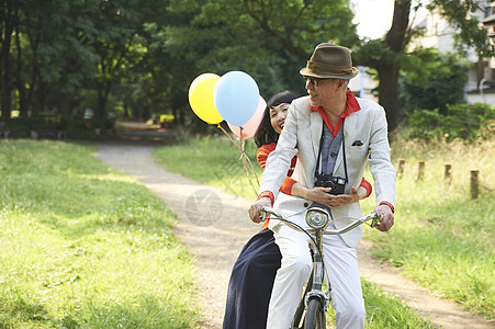 双人自行车公园里骑自行车的甜蜜夫妇背景