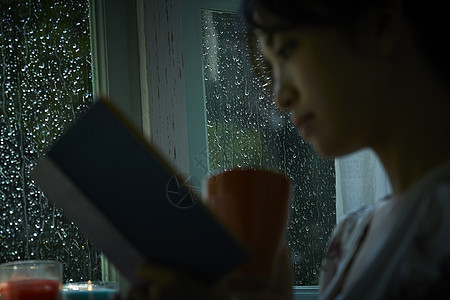 下雨天在家休息看书的女性图片