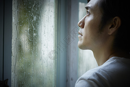 下雨天在室内的孤独男性图片