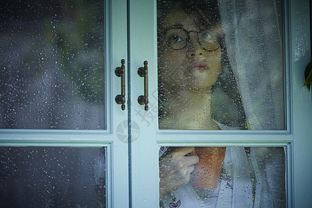 下雨天看向窗外的女青年背景图片