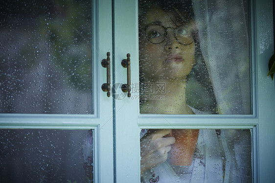 下雨天看向窗外的女青年图片