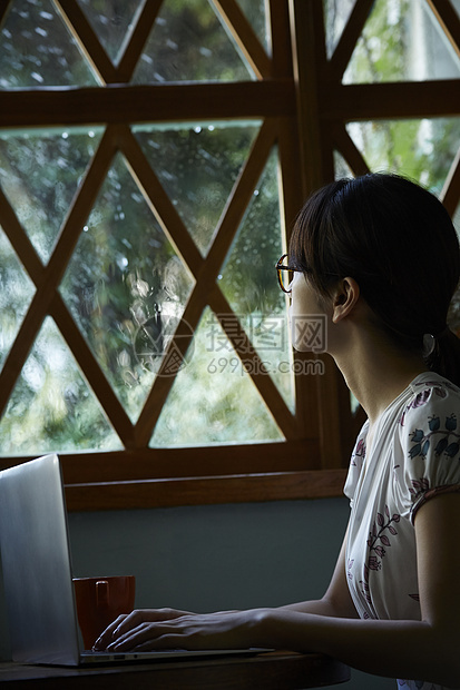 下雨天咖啡馆看向窗外的年轻女性图片