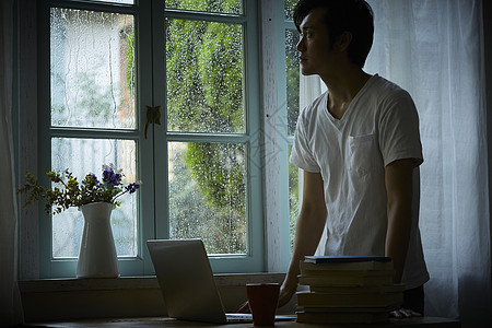 下雨天居家看向窗外的成年男子图片