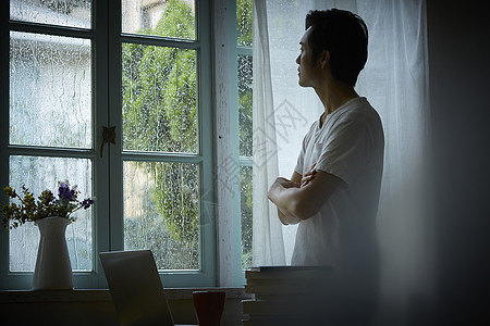 下雨天看向窗户外的成年男性图片