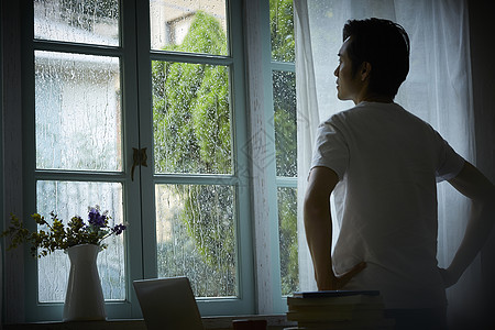 下雨天成年男子看着雨打湿的窗户图片