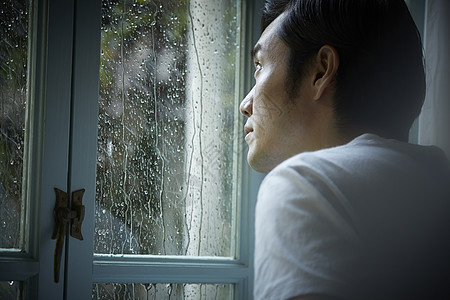 下雨天看向窗外的男性图片