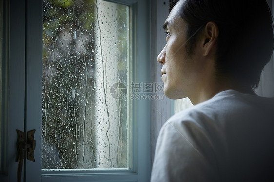 雨天看着窗外的成年男子图片