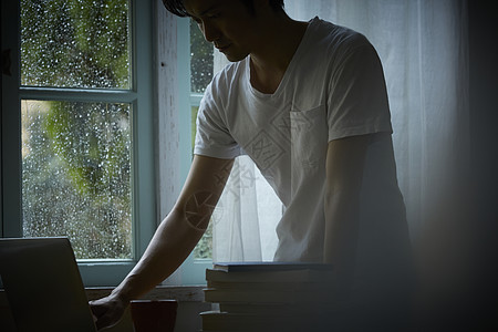 下雨天居家使用笔记本电脑的成年男子图片