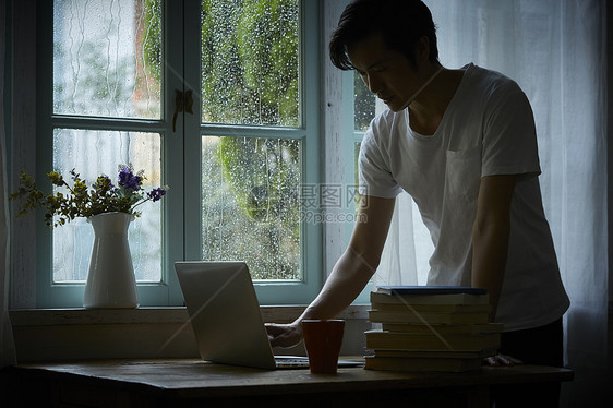 下雨天居家工作的成年男人图片