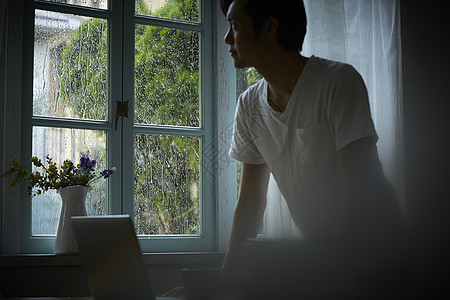 下雨天居家看着窗外的男人图片