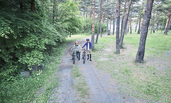 树林里推着山地车行走的夫妇图片