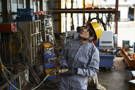 工厂穿着工作服头盔操作机器的工人图片