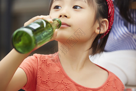 拿着饮料瓶喝的小女孩图片
