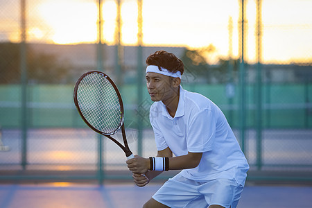 日落网球场打网球的男性图片