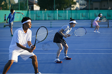 户外网球场打网球双打的青年男女图片