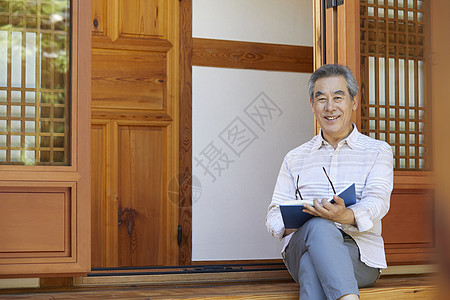 老年男性屋前阅读图片