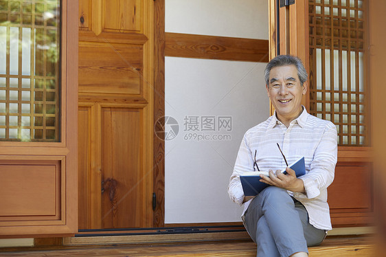 老年男性屋前阅读图片