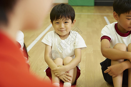小姑娘双臂抱膝坐于地板上室内孩子们在体育课教学教学故事图片