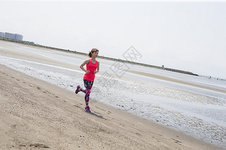 在沙滩边上跑步的运动少女图片