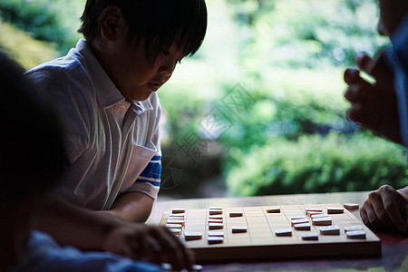 看着电脑的男孩看着棋盘下棋的小男孩背景