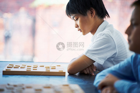 看着棋盘沉思的小男孩图片