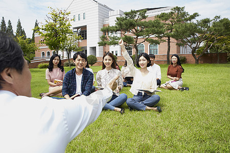 大学教授和学生们围坐在草地上分享交流图片