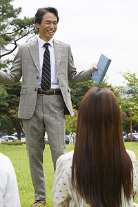 大学教授和学生们围坐在草地上分享交流图片