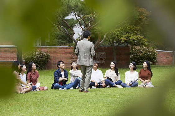 大学教授和学生们围坐在草地上分享交流图片